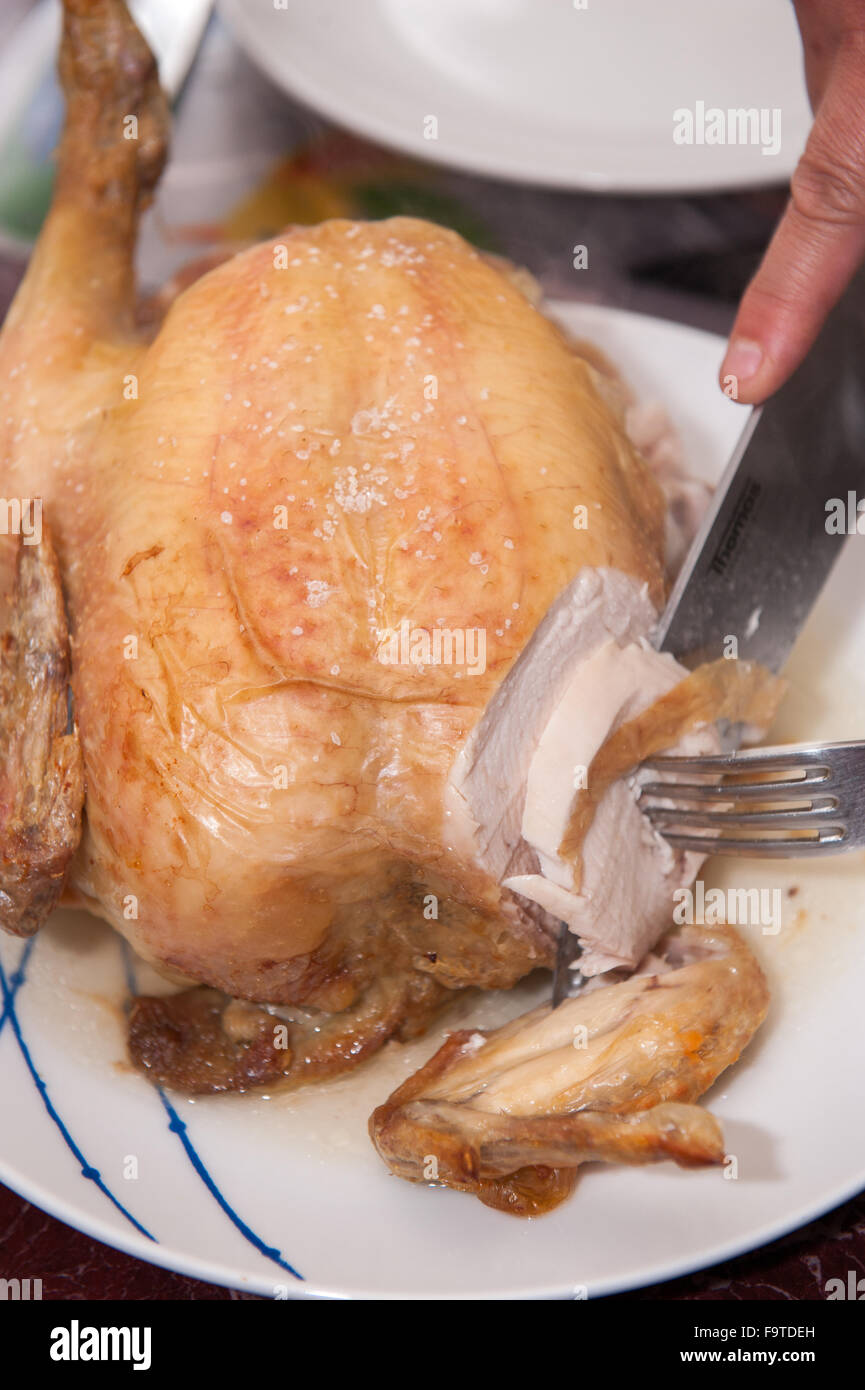 Cooked chicken being sliced at table Stock Photo