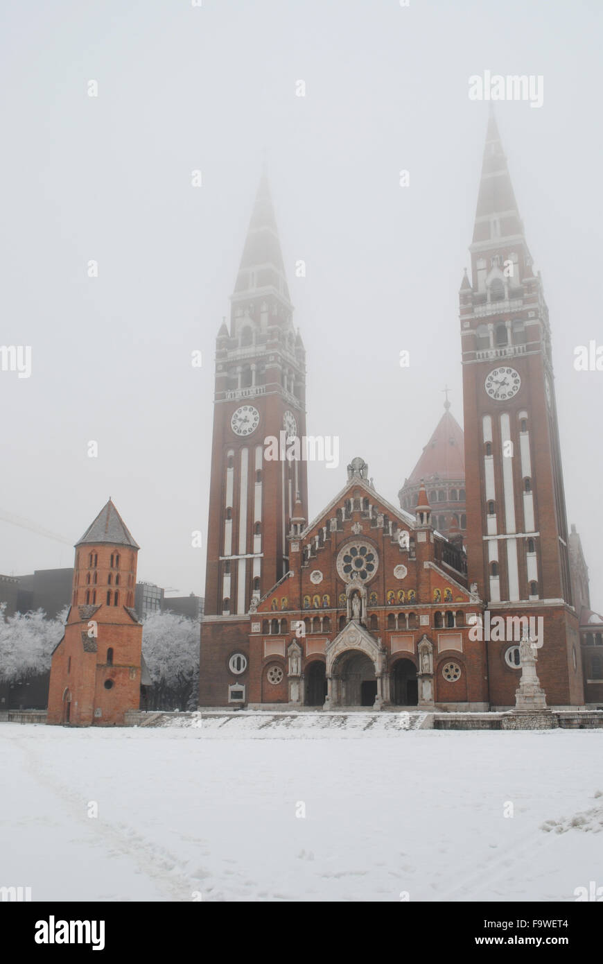 The Votive Church, the Demetrius Tower and the snowy Dom Square in Szeged, Hungary. Stock Photo