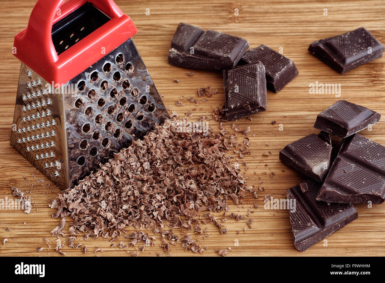 Chocolate, grater and grated chocolate on a chopping board Stock