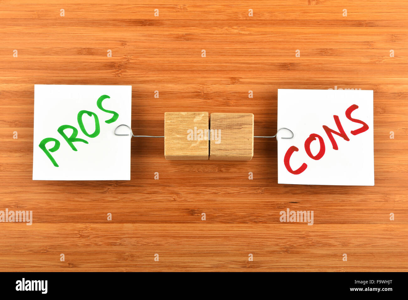 Choice, dilemma, two white paper notes with marker writter pros and cons words, wooden holders in different directions on bamboo Stock Photo