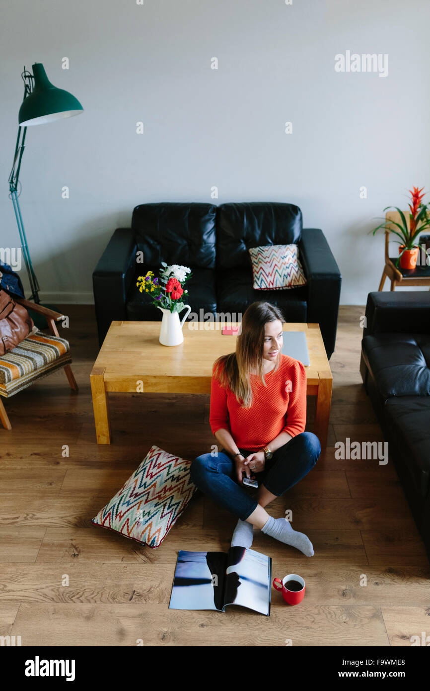 Young woman sitting on the floor of her living room relaxing Stock ...