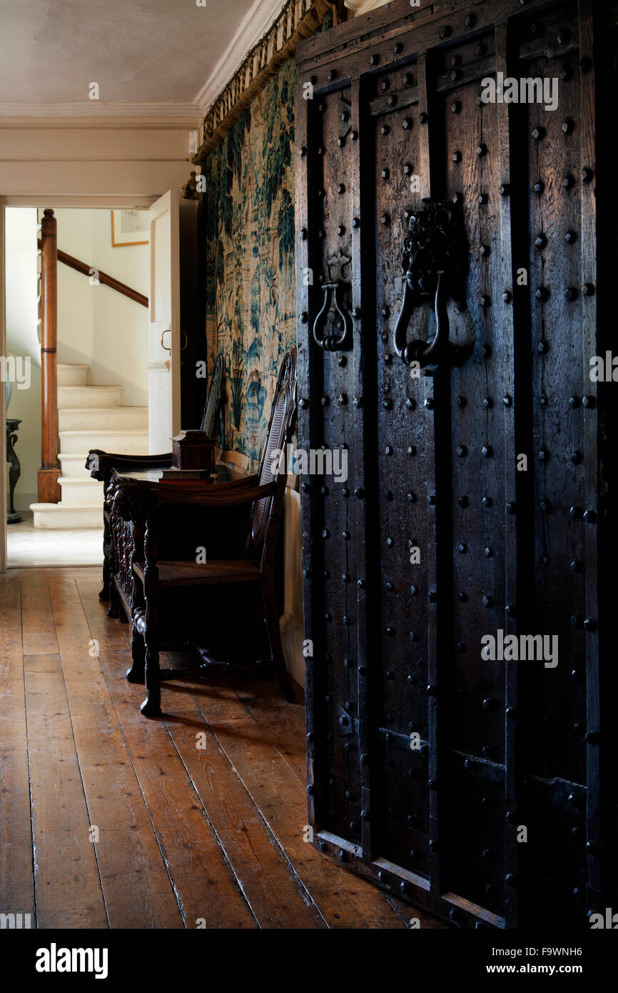 UK real estate. Old studded front door opening onto antiques furnished entrance hall. Stock Photo