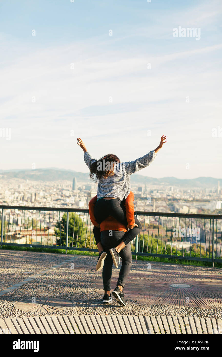 Spain, Barcelona, backview of young man giving his girlfriend a piggyback ride Stock Photo