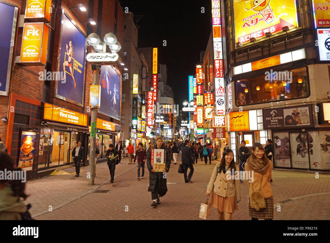 People milling around Shibuya district at night lit up by advertising ...