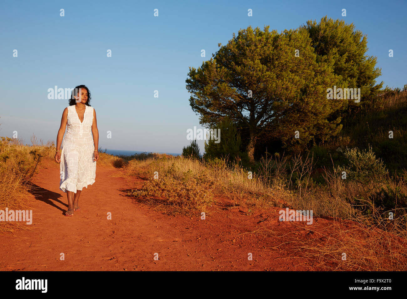 Woman walking on a country road Stock Photo - Alamy