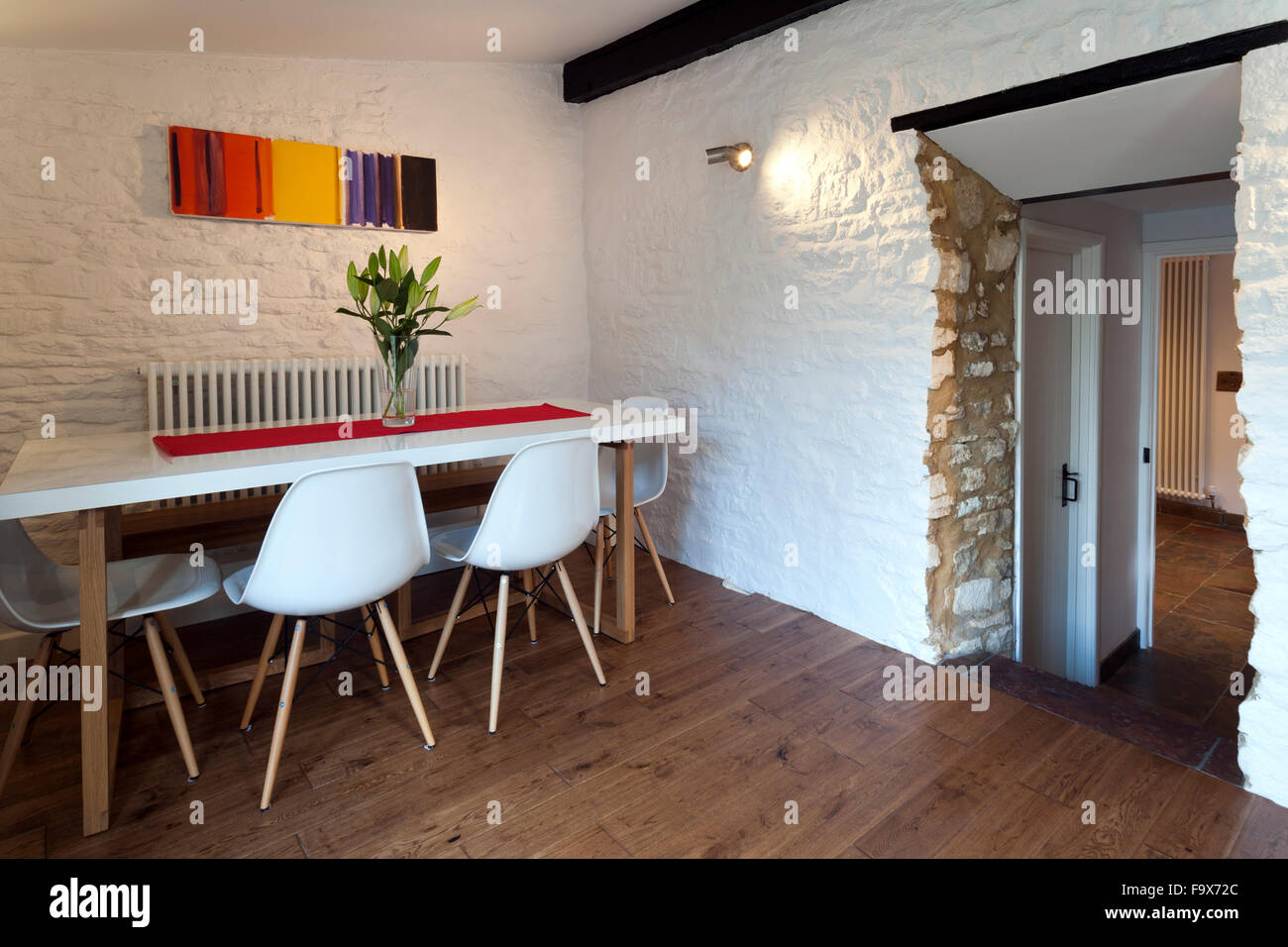 Contemporary style dining room in an old cottage, white painted stone walls. Stock Photo