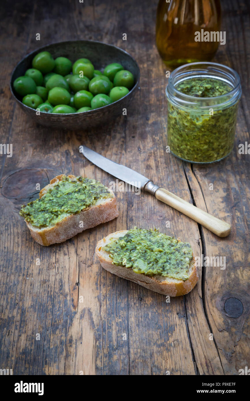 Bowl of green olives, carafe with olive oil, knife and slices of bread