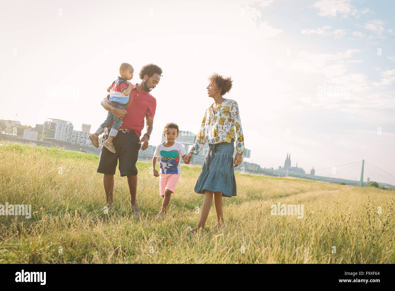 Germany, Cologne, family of four walking in a field Stock Photo