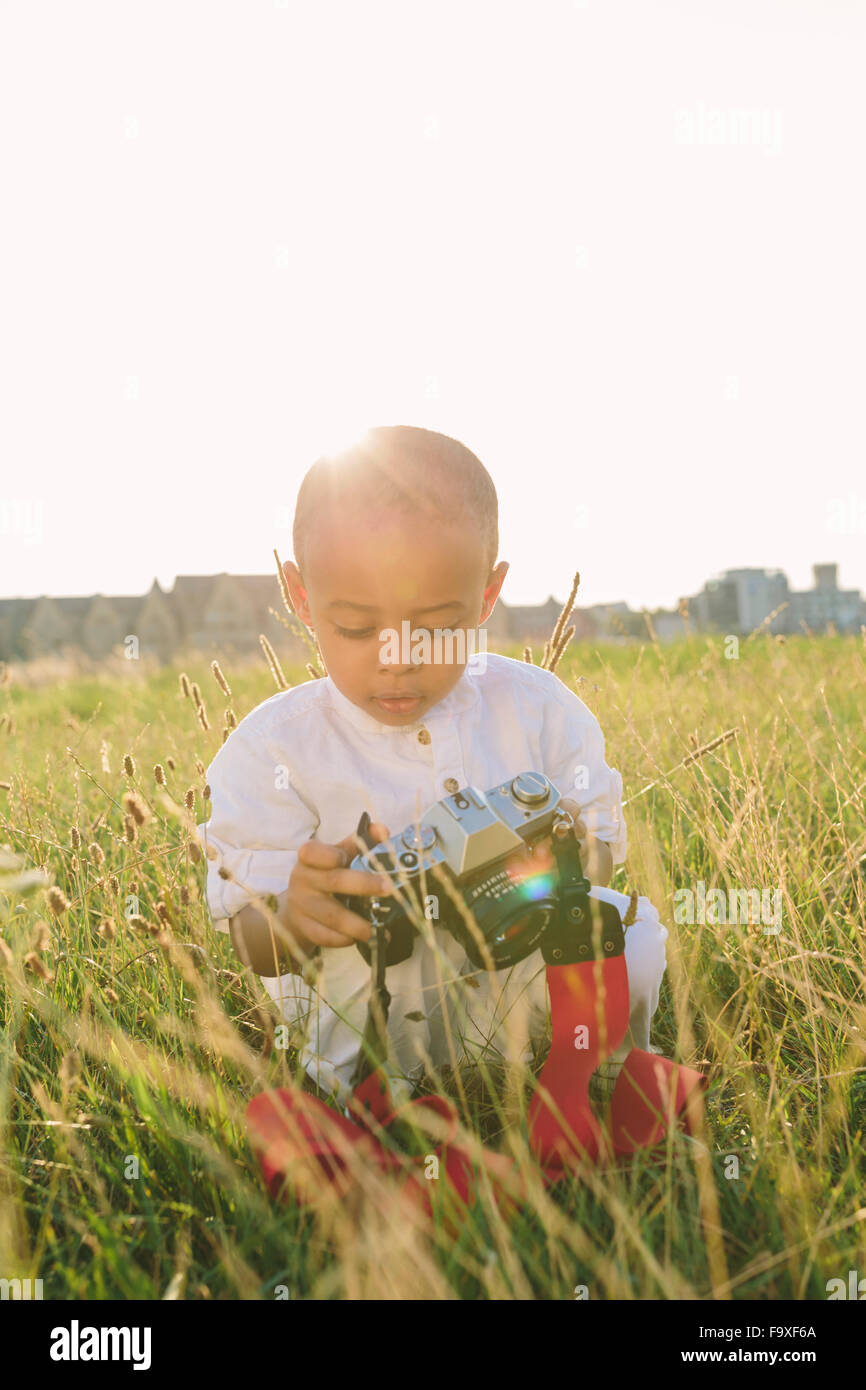 Boy sitting in field looking at camera Stock Photo - Alamy