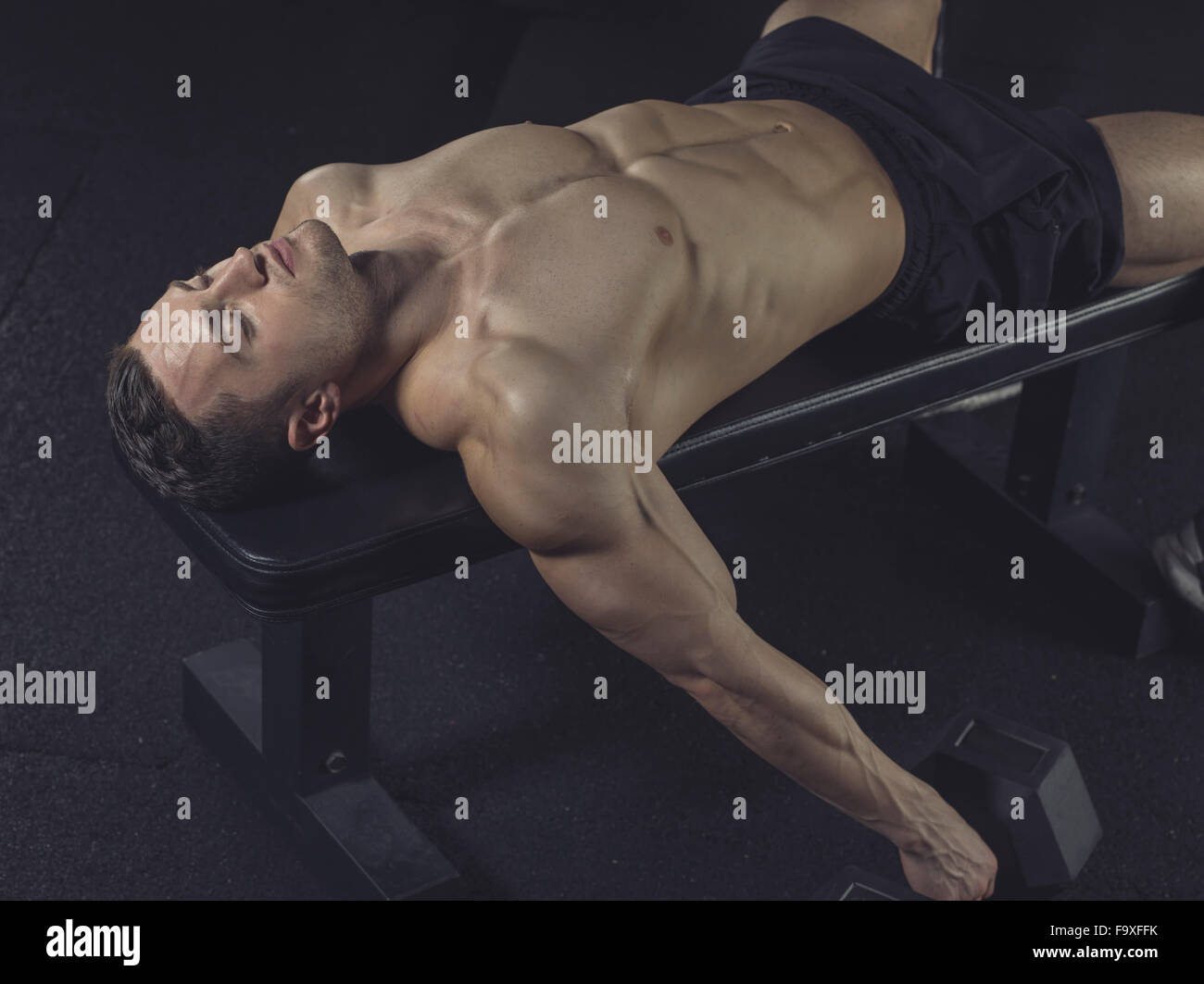 Physical athlete lying on gym machine Stock Photo