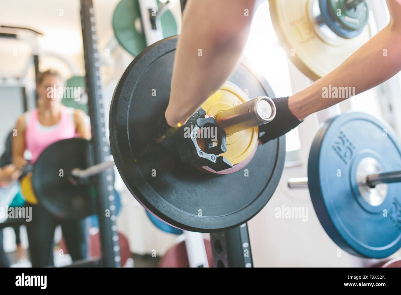 Closeup of woman's hand putting weights on a barbell in gym Stock