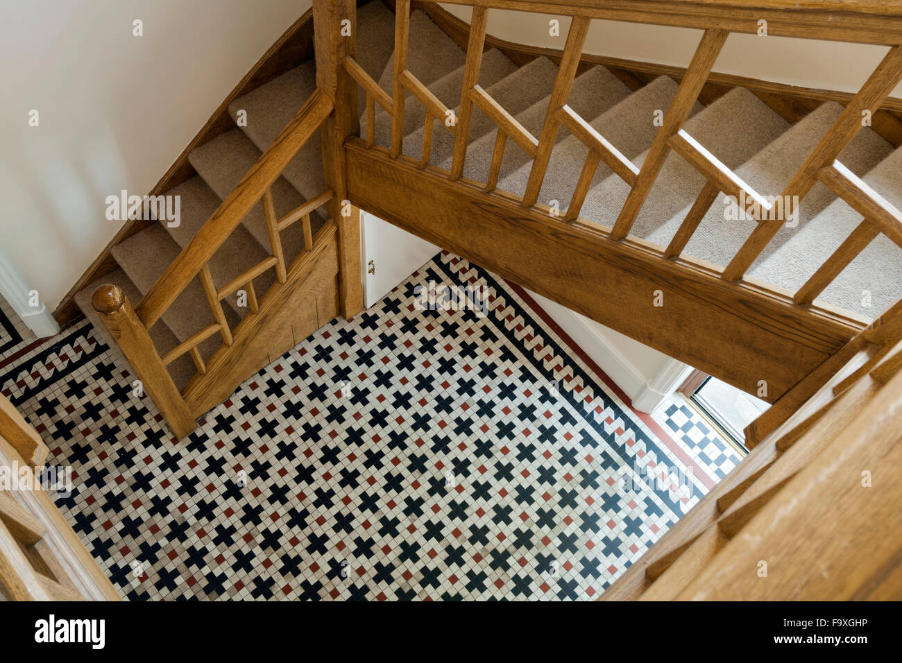 UK real estate. Looking down from a contemporary staircase to a Victorian geometric tiled floor. Stock Photo