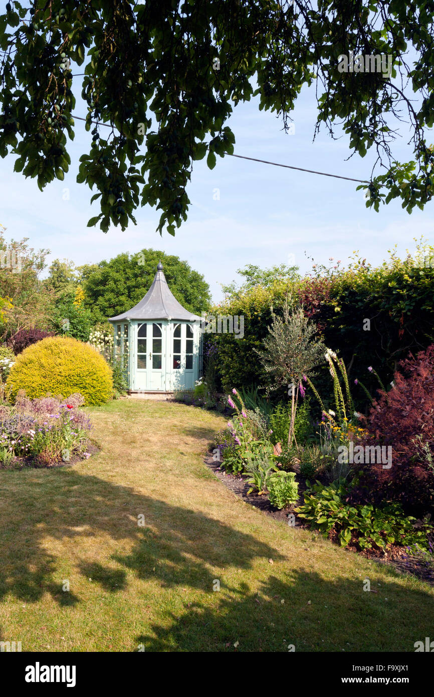 UK gardens. An octagonal painted summerhouse in a summer garden. Stock Photo
