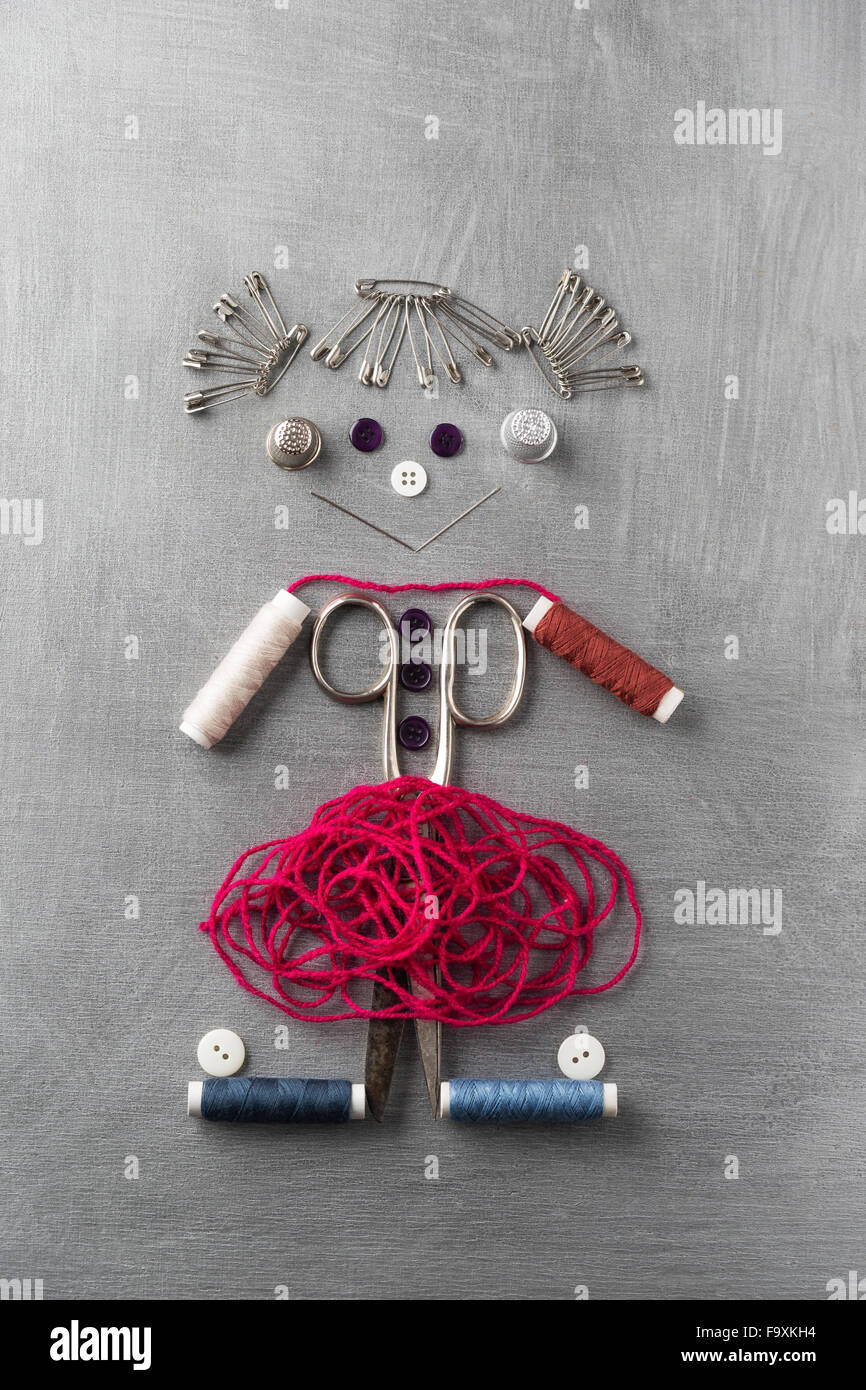 Sewing items building figur of a smiling girl on grey background Stock Photo