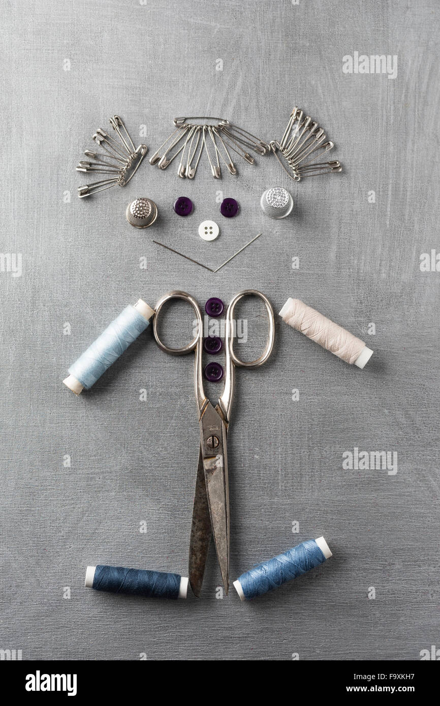 Sewing items building figur of a smiling girl on grey background Stock Photo