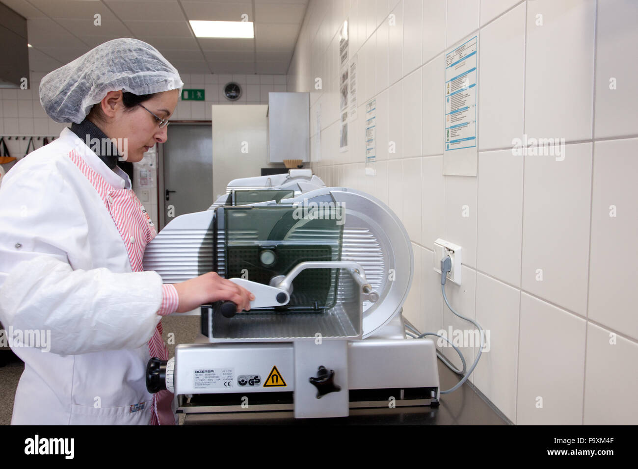 Larder cook cuts assortment of sliced sausage at a machine Stock Photo