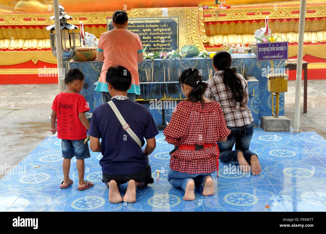 Pattaya, Thailand Devout Thai family kneeling in prayer at a shrine in