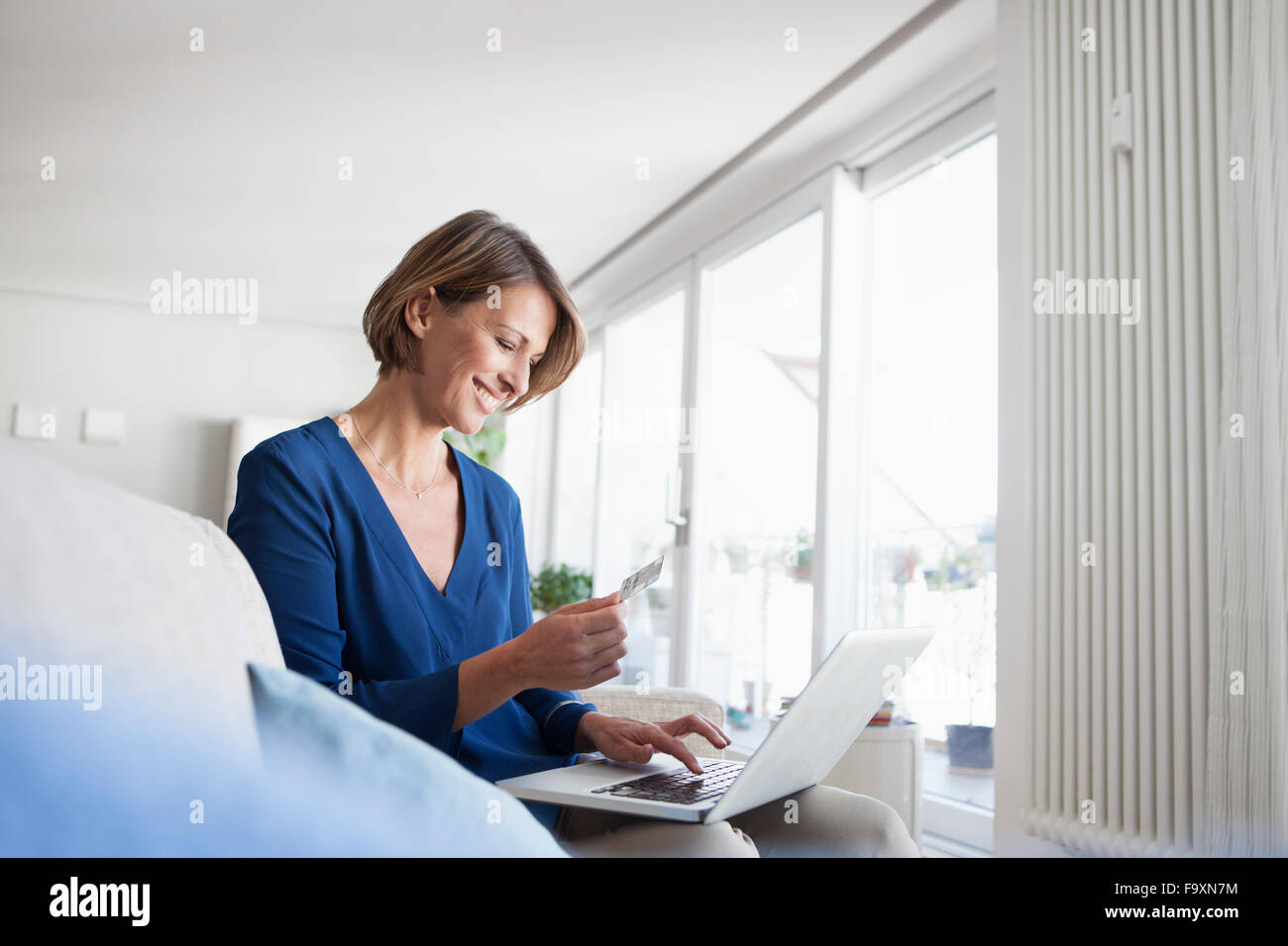 Smiling woman at home shopping online Stock Photo