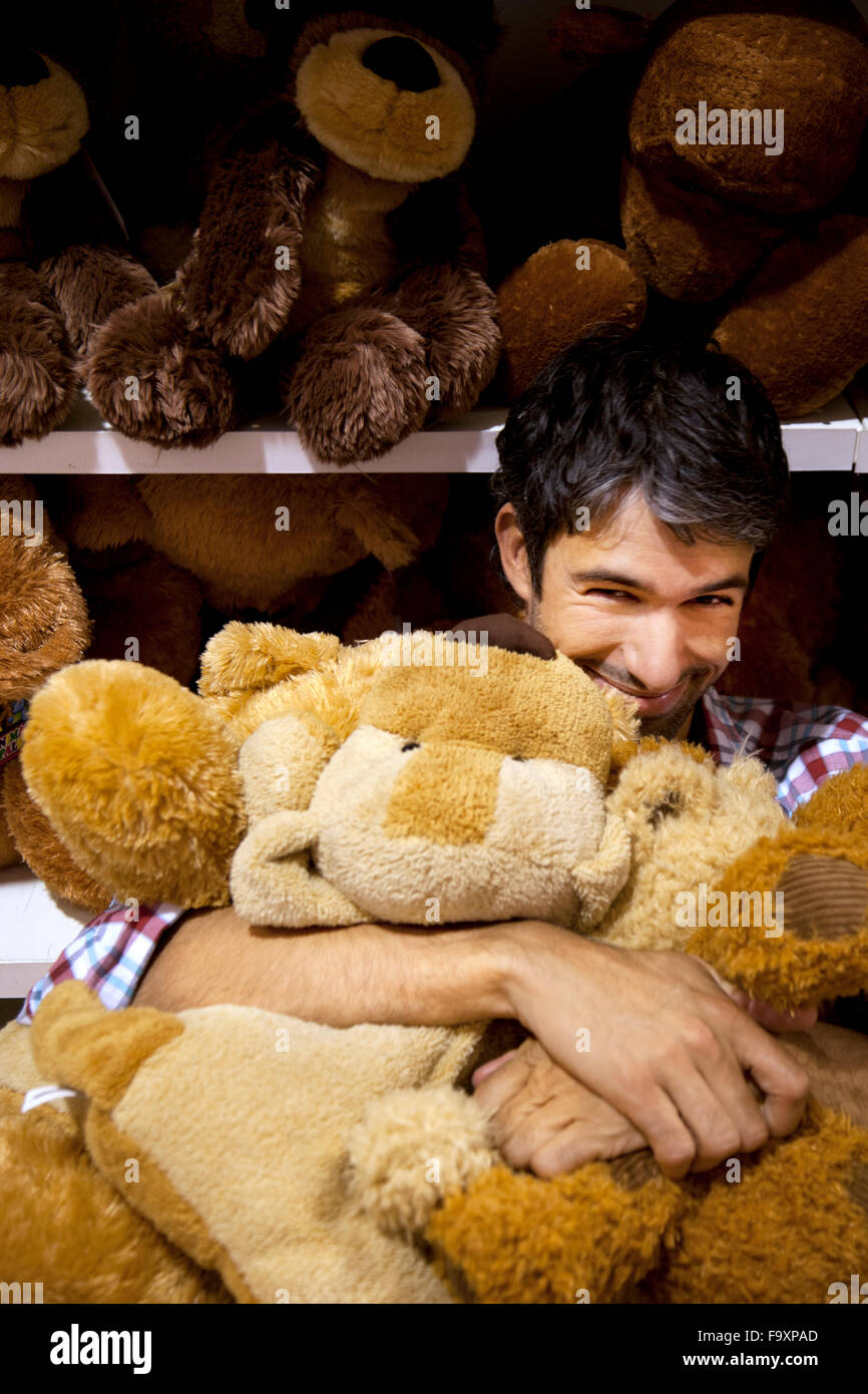 Smiling man hugging teddy bears in a shop Stock Photo