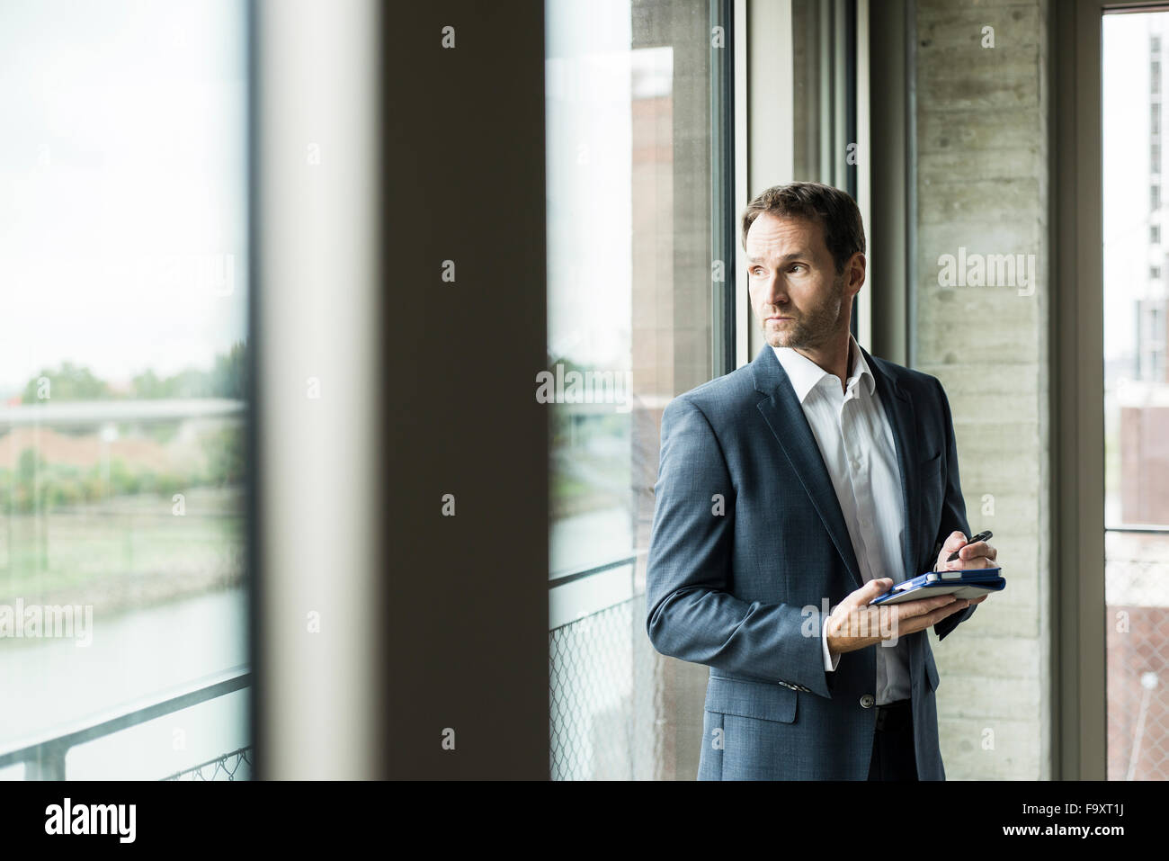 Portrait of businessman looking through window Stock Photo