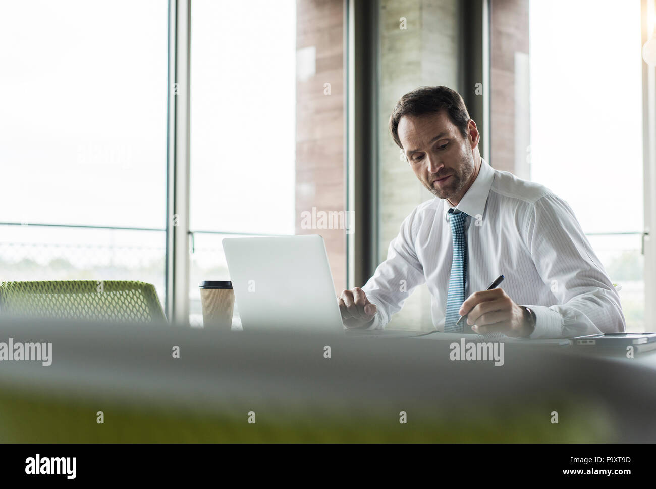 Portrait of businessman writing at his desk in the office Stock Photo