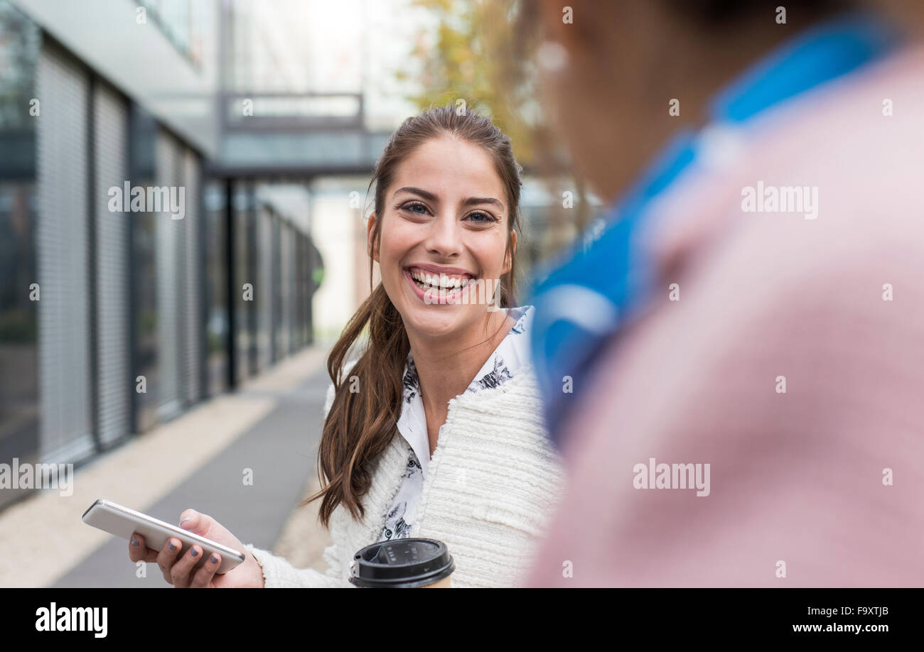 Smiling young woman looking at colleague outdoors Stock Photo