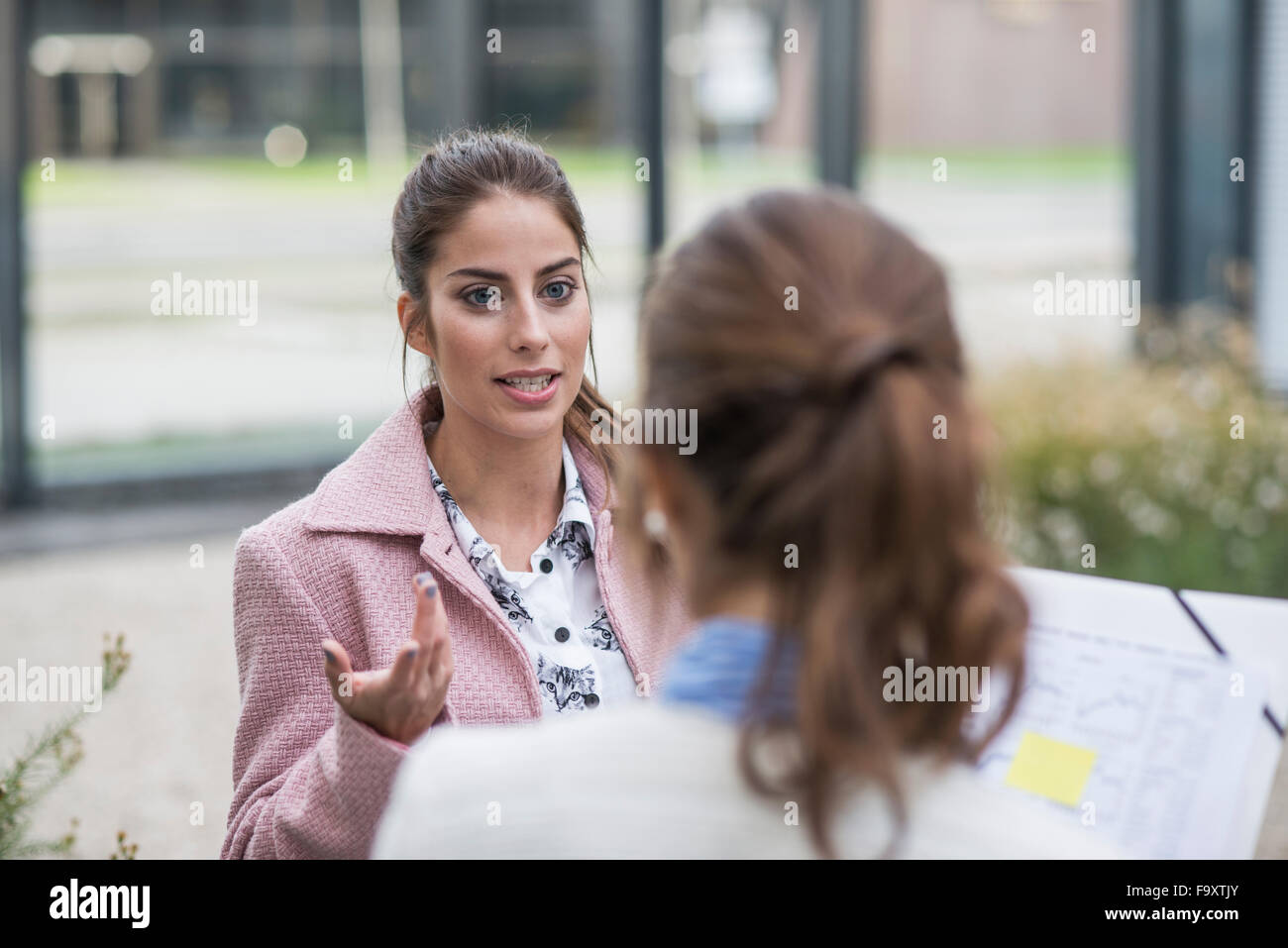 Young woman talking to colleague outdoors Stock Photo