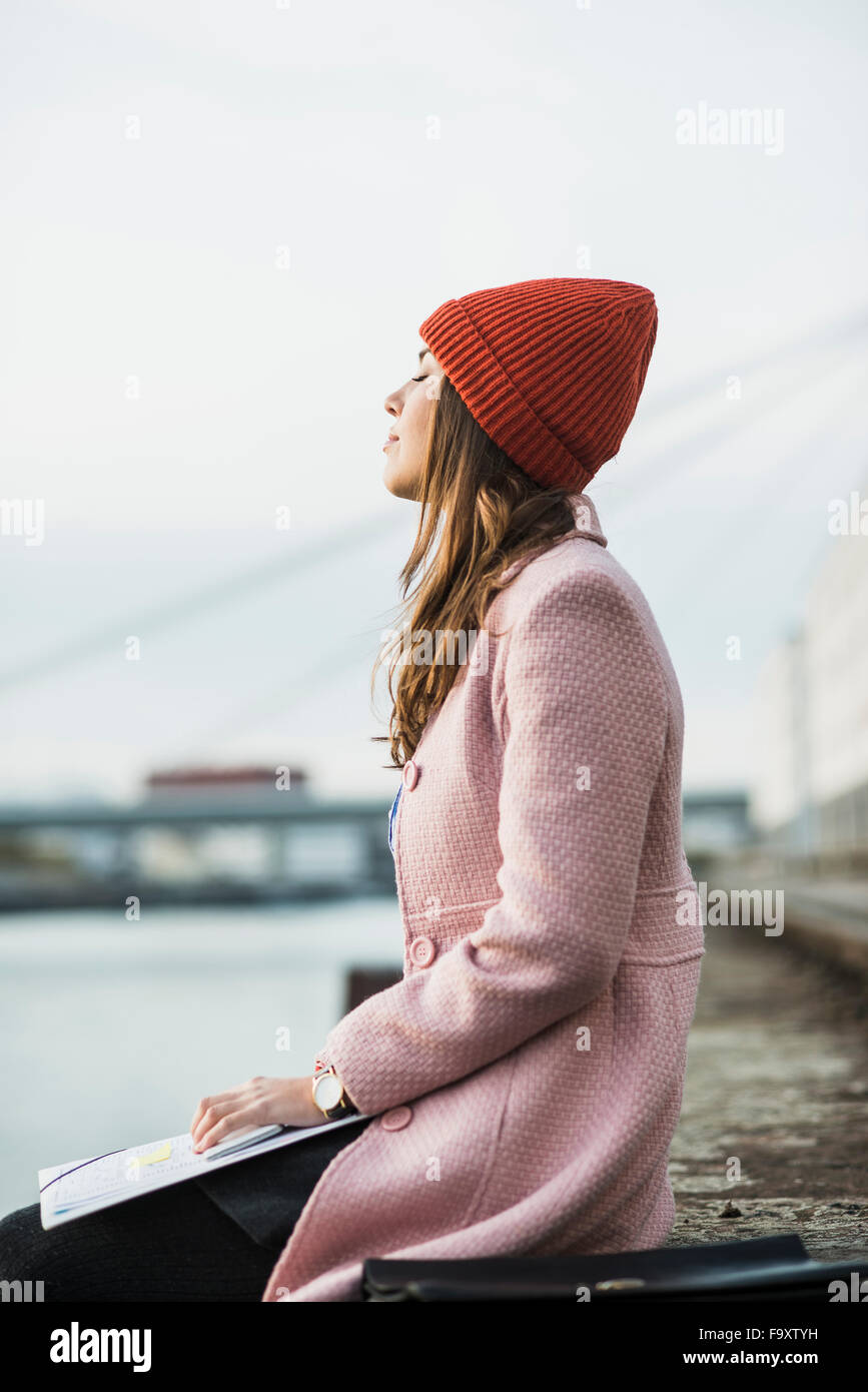 Young woman sitting at the riverside relaxing Stock Photo