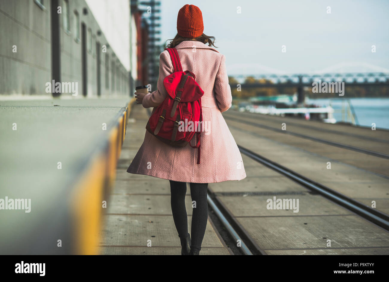 Young woman with backpack walking at the riverside Stock Photo