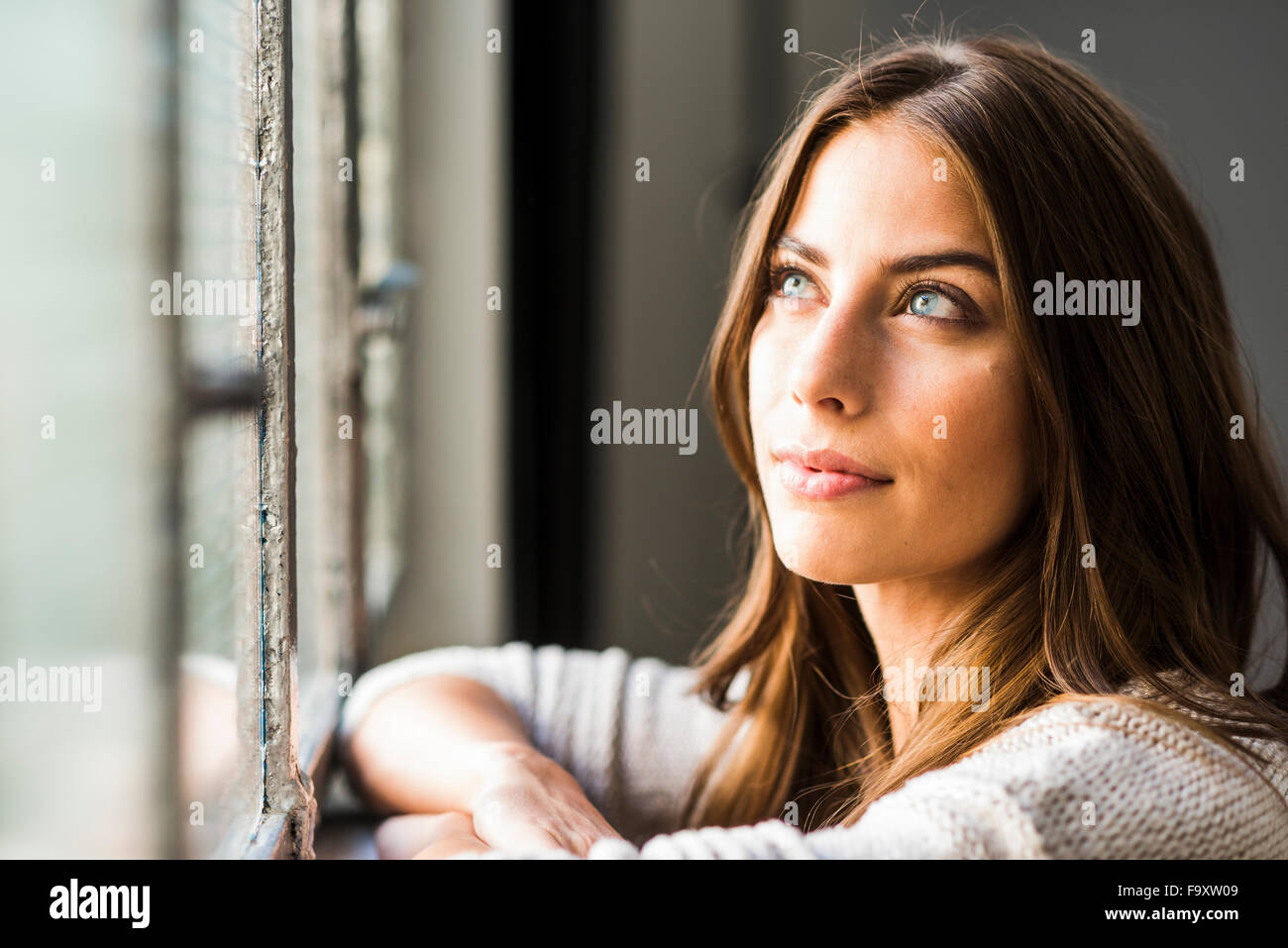 Brunette woman looking out of window Stock Photo