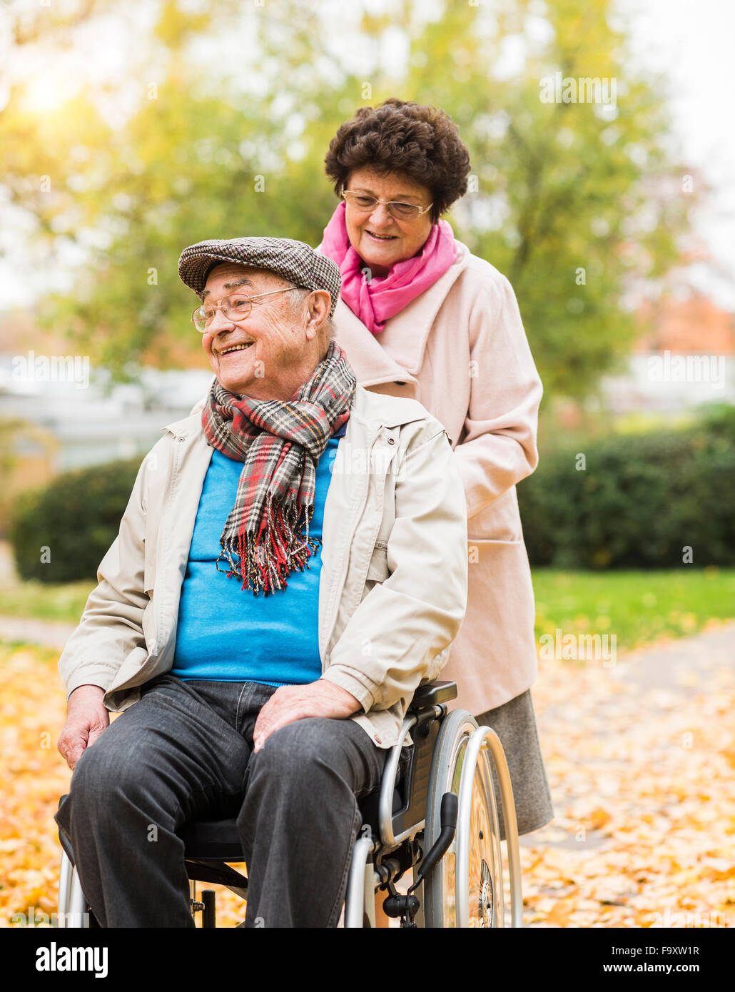 Senior woman pushing husband in wheelchair Stock Photo