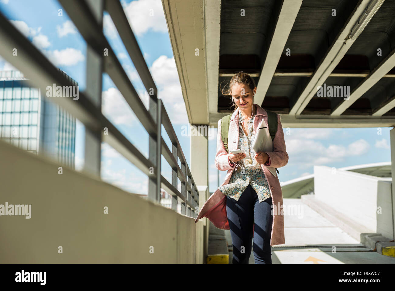 Young woman with earbuds and cell phone in parking garage Stock Photo