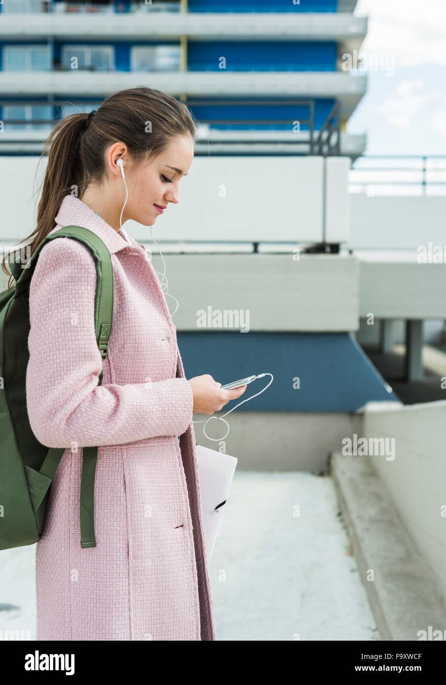 Young woman with earbuds looking at cell phone Stock Photo