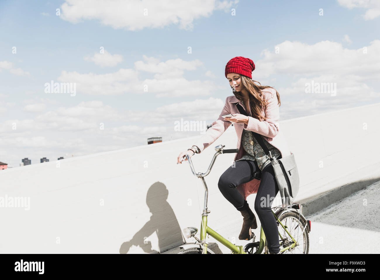 Young woman on bicycle looking at cell phone Stock Photo