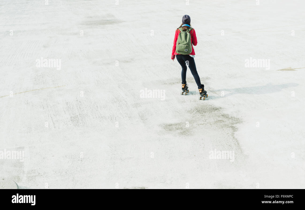 Young woman with backpack inline skating on parking level Stock Photo