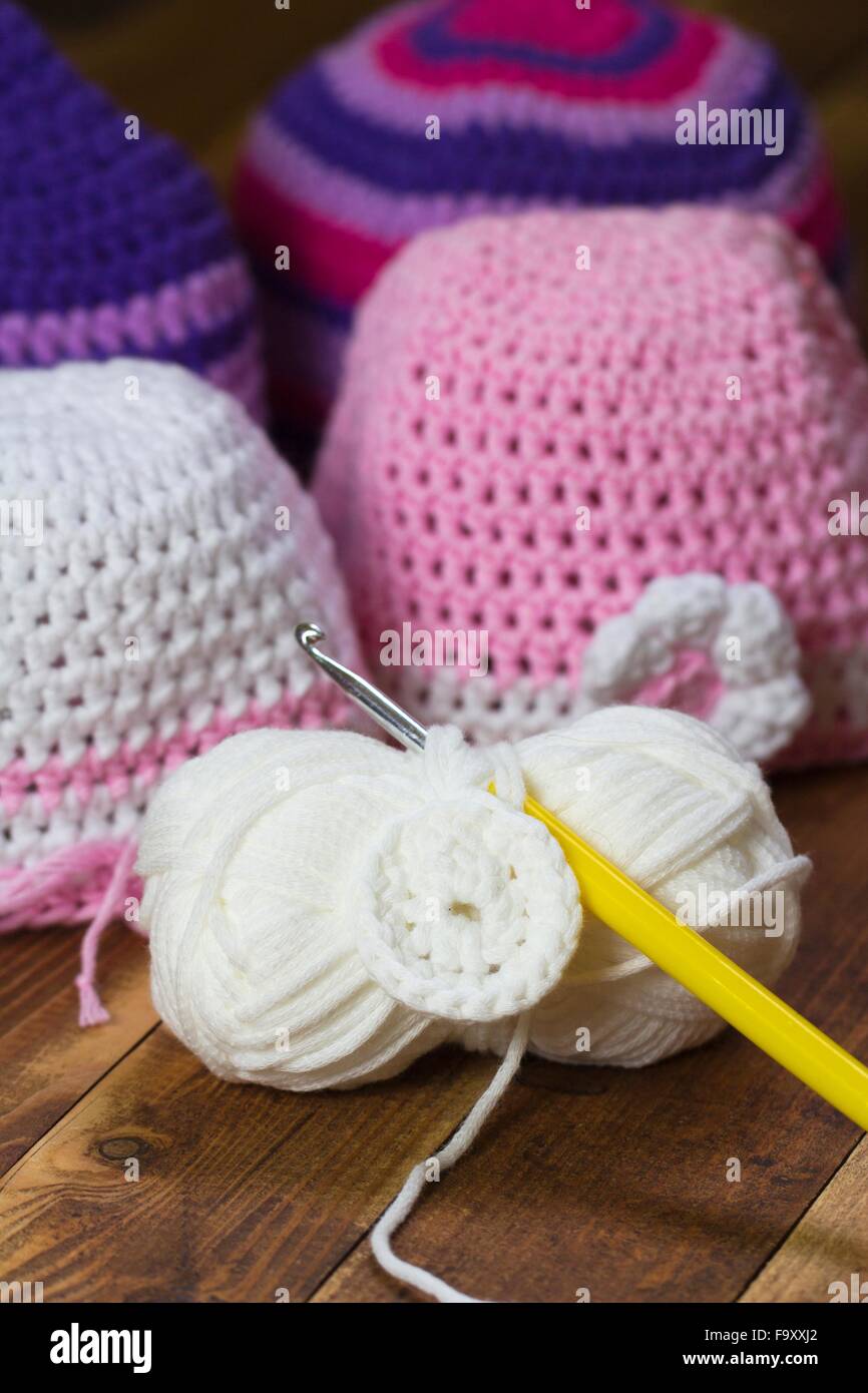 Crocheted caps, crochet hook and a ball of wool Stock Photo