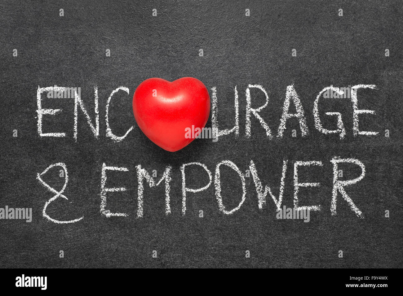encourage and empower words handwritten on blackboard with heart symbol instead O Stock Photo