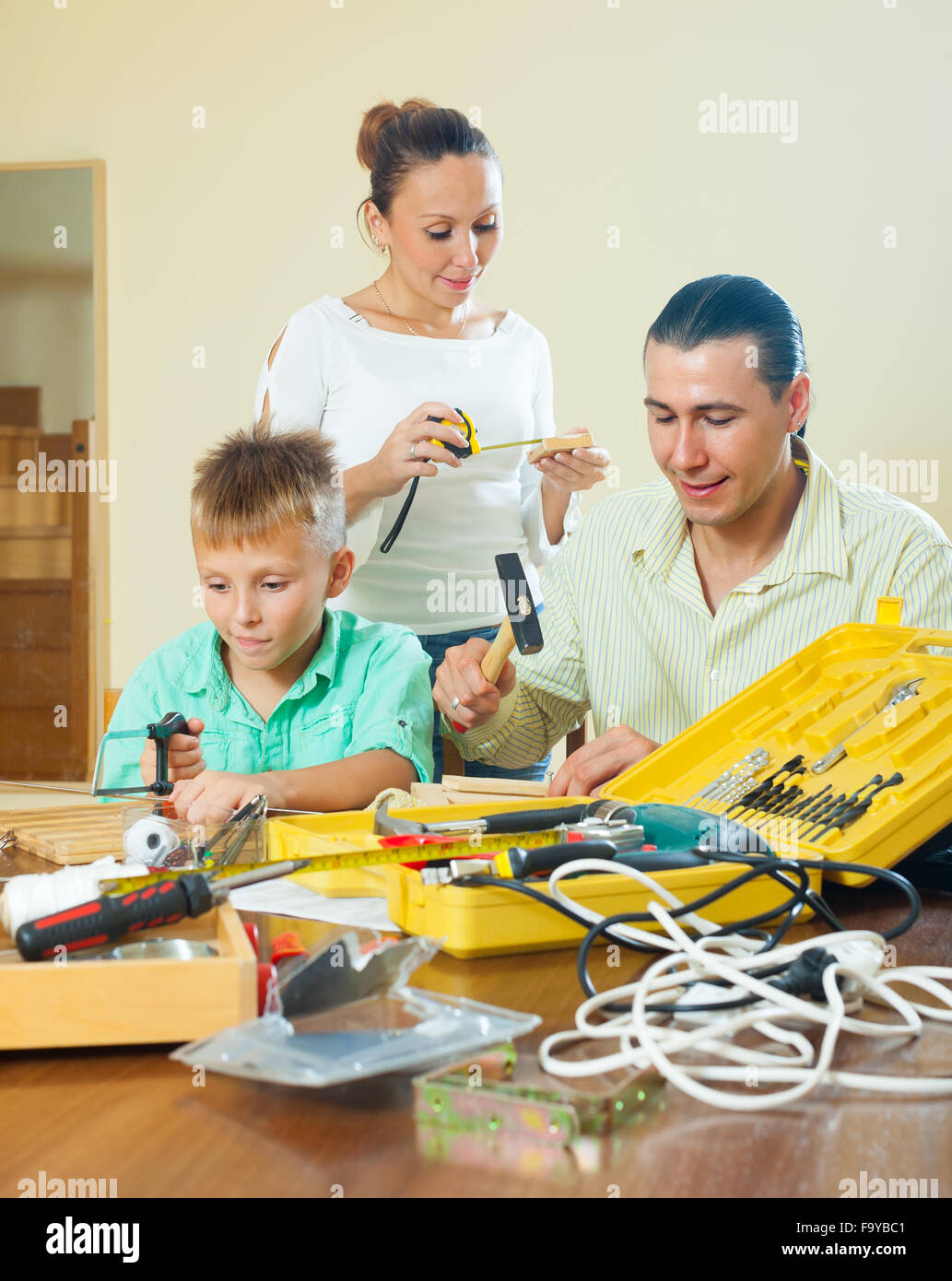 Happy family of three doing something with working tools at home Stock Photo