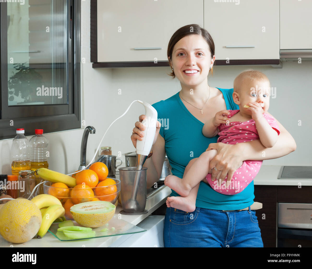 Happy woman with child together cooking fruit puree  in kitchen Stock Photo