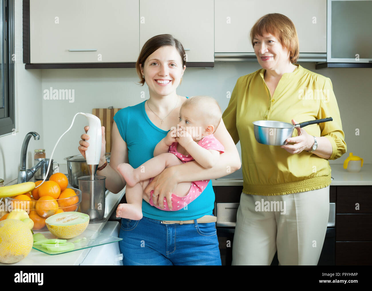 Happy women with blender cooking fruit puree in domestic kitchen at home Stock Photo