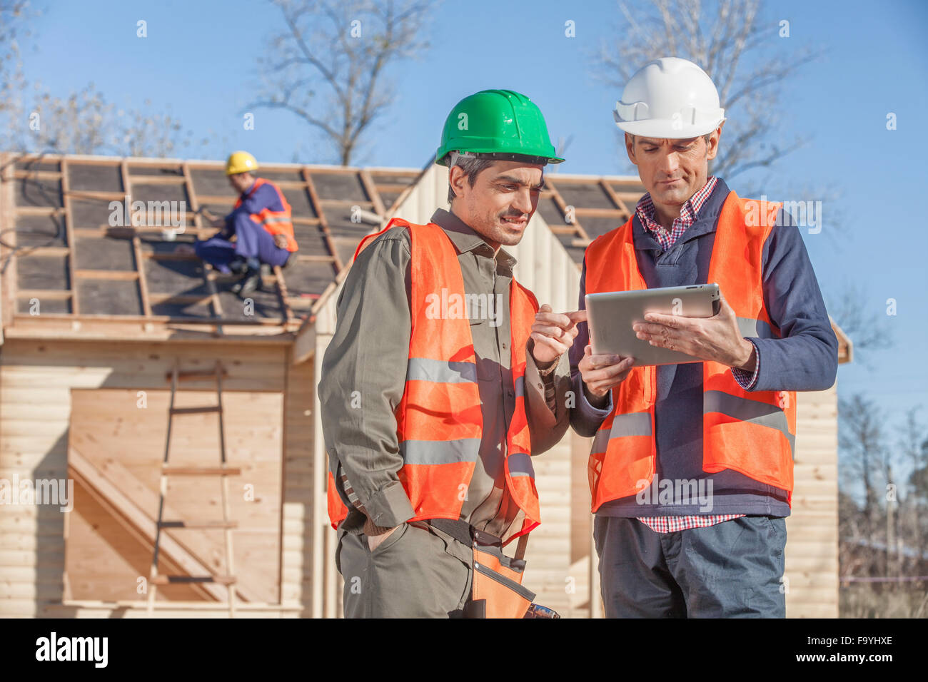 3 person construction crew standing in front of newly built house Stock Photo