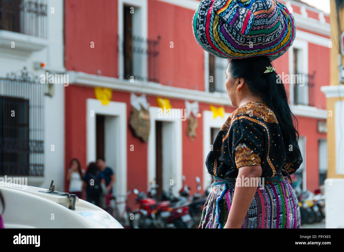 Woman With Tied Cloth bag on Her Head walking the street of Antigua Stock Photo