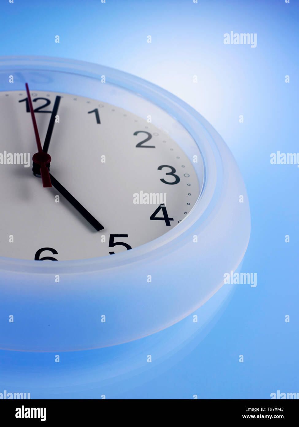 Close up of Clock showing 5 o'clock on a blue wall Stock Photo