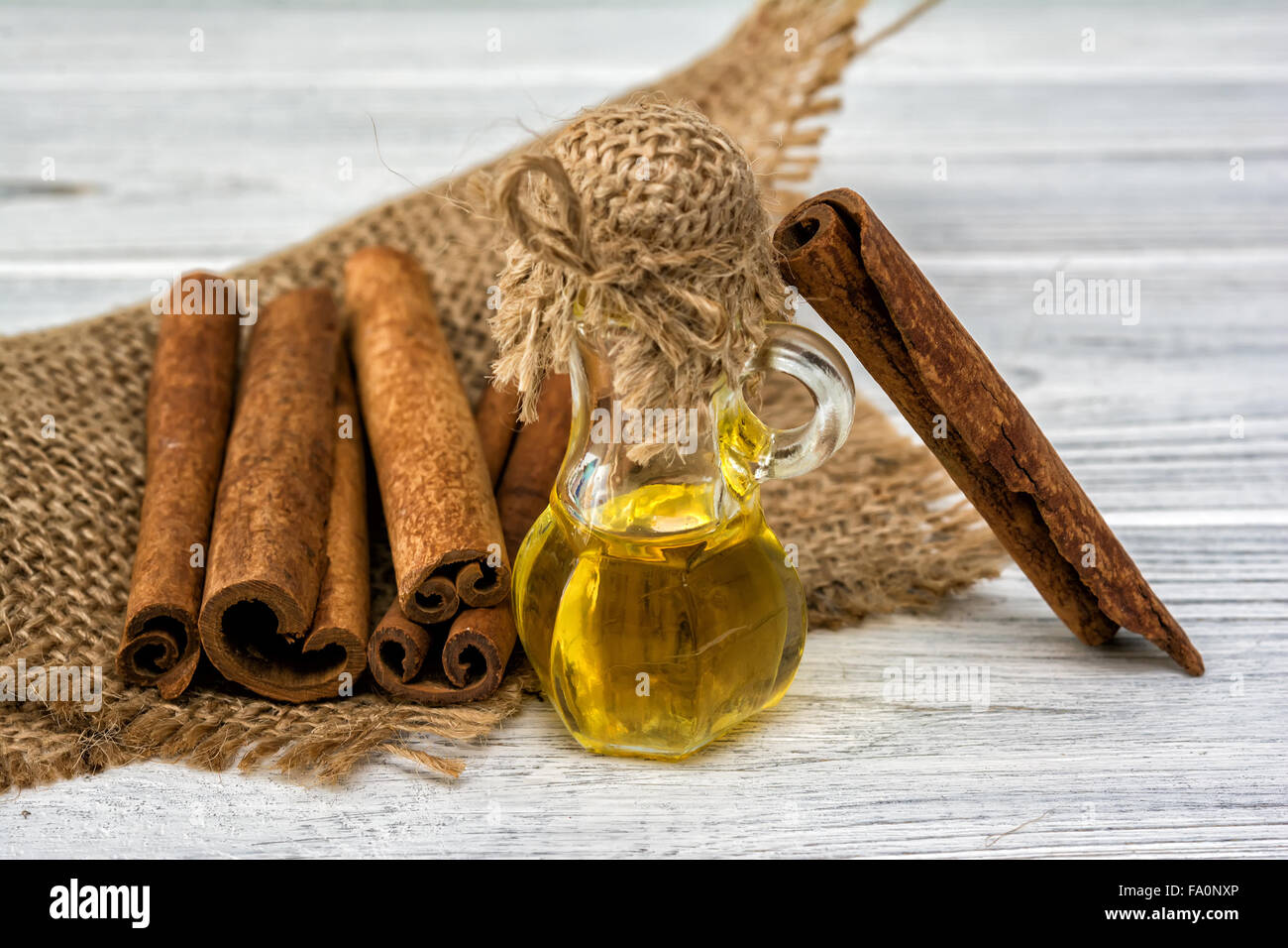Essential cinnamon oil in bottle and cinnamon cticks on sackcloth Stock Photo