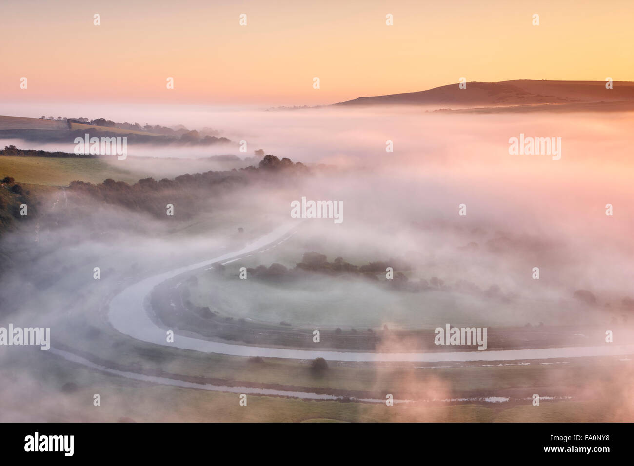 Mist floating over the river valley below with warm morning sunlight Stock Photo