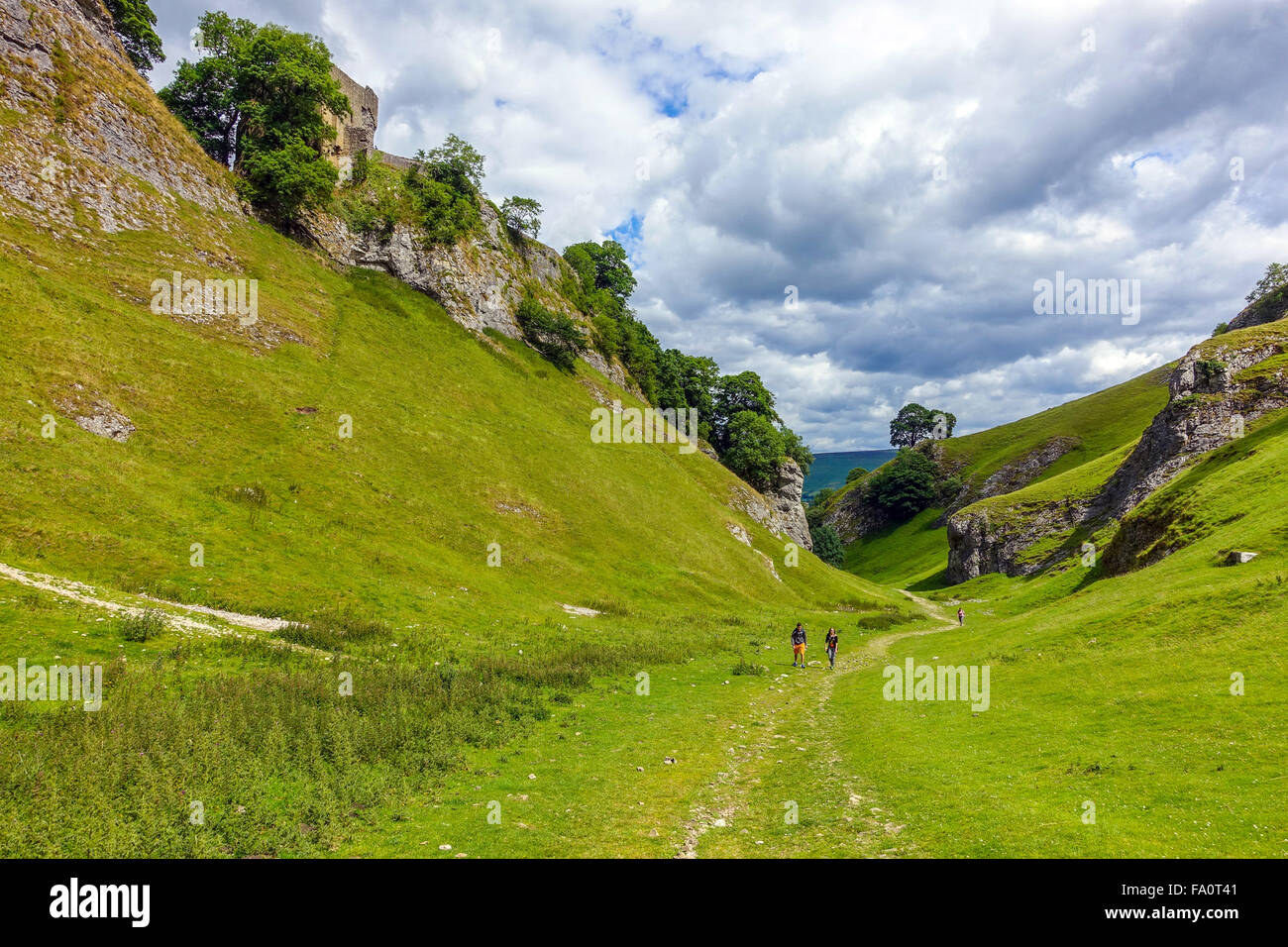 Three walkers hikers in Cavedale with Pevril Castle, Castleton Stock Photo