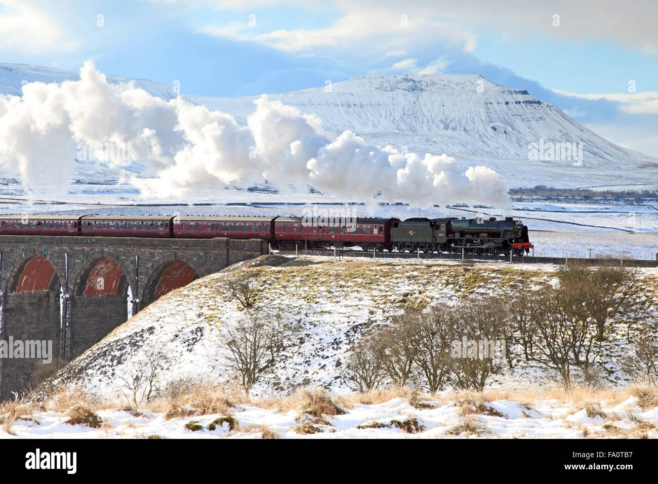 46115 Scots Guardsman passing over Ribblehead Viaduct with a snowy Ingleborough in the background, North Yorkshire Stock Photo