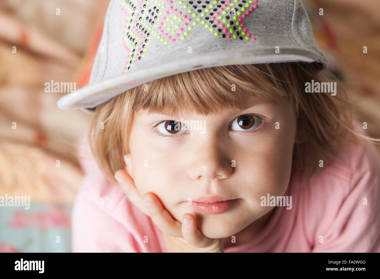 Closeup portrait of thinking cute Caucasian blond baby girl in gray cap Stock Photo