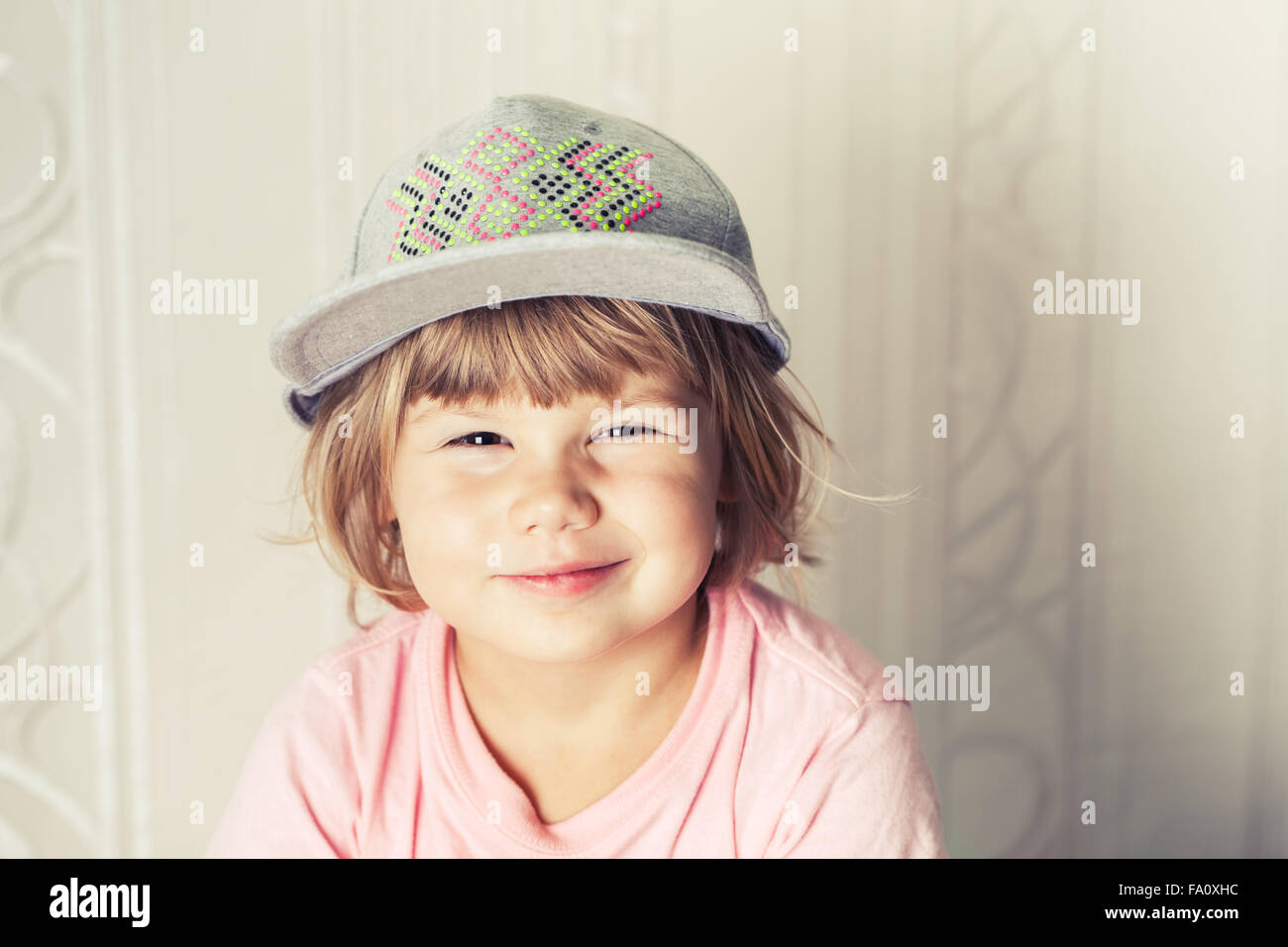 Closeup portrait of smiling cute Caucasian blond baby girl in gray cap, warm vintage tonal correction photo filter Stock Photo