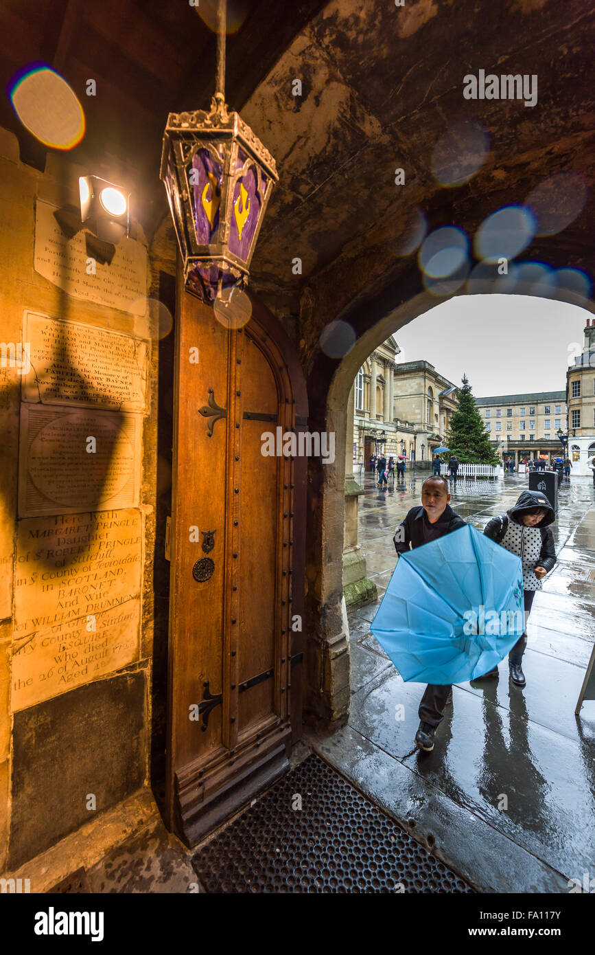 Shoppers rush to take shelter from the heavy rain in the entrance of Bath Abbey on 'Panic Saturday' on the last weekend before Christmas. Stock Photo
